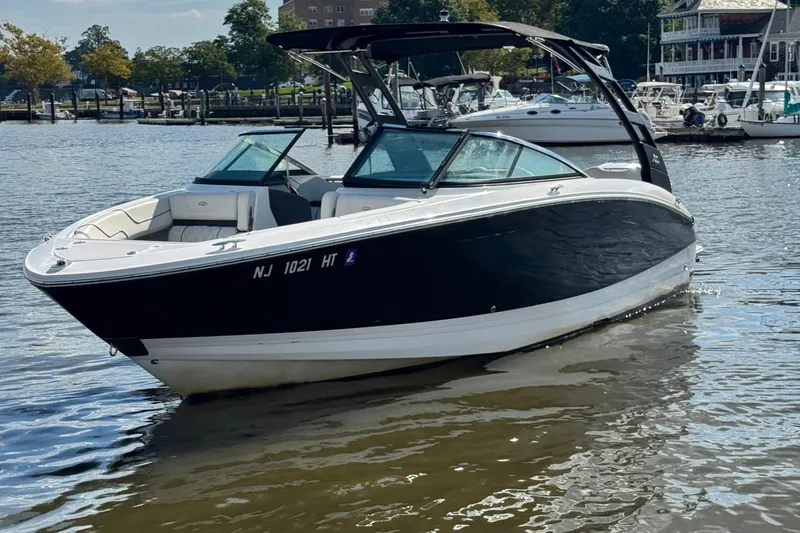 The Image of 2024 Regal LX6 boat on calm water, docked near a marina. - 0
