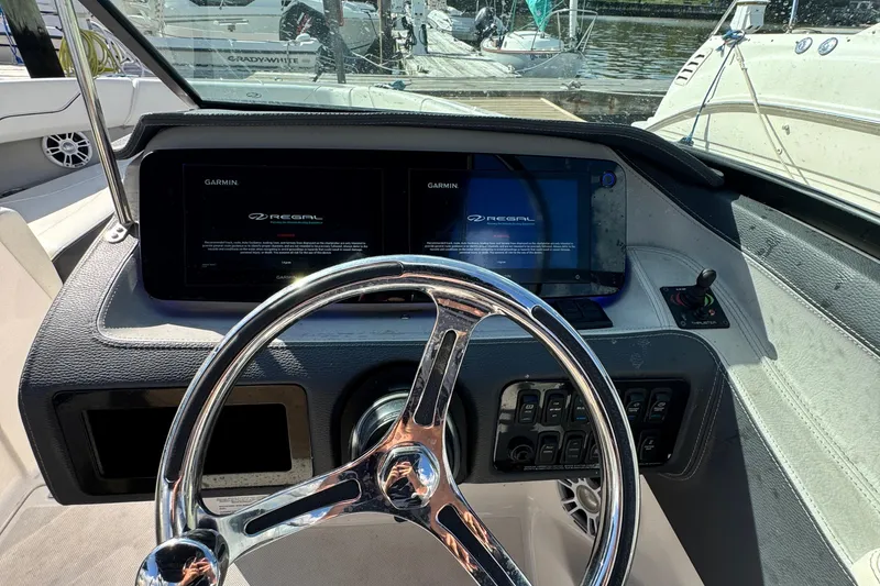 Slide: The Image of 2024 Regal LX6 boat dashboard with Garmin displays and steering wheel. - 14