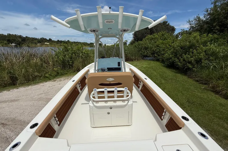 Slide: The Image of 2026 Pathfinder 2400 TRS boat with seating, docked near lush greenery and water. - 13