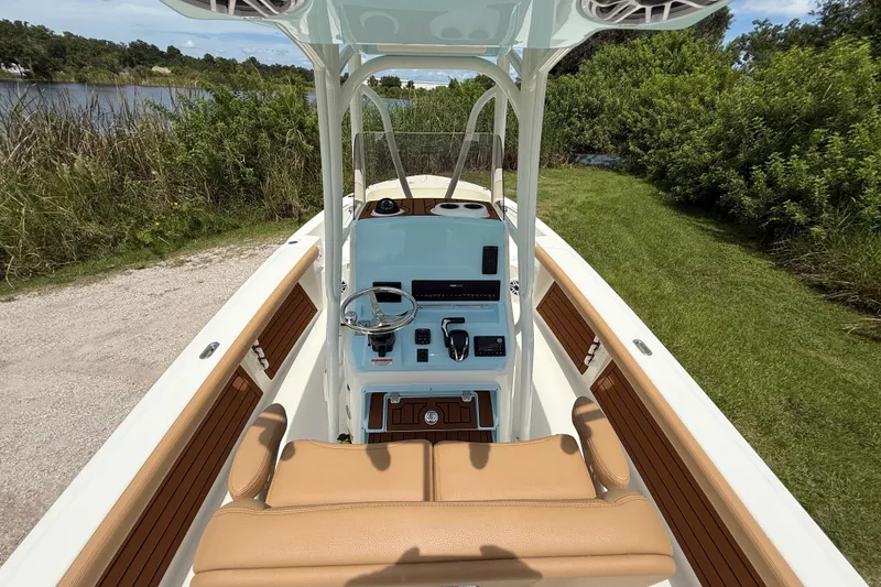 Slide: The Image of 2026 Pathfinder 2400 TRS boat interior with steering console, tan seating, and lush greenery backdrop. - 14