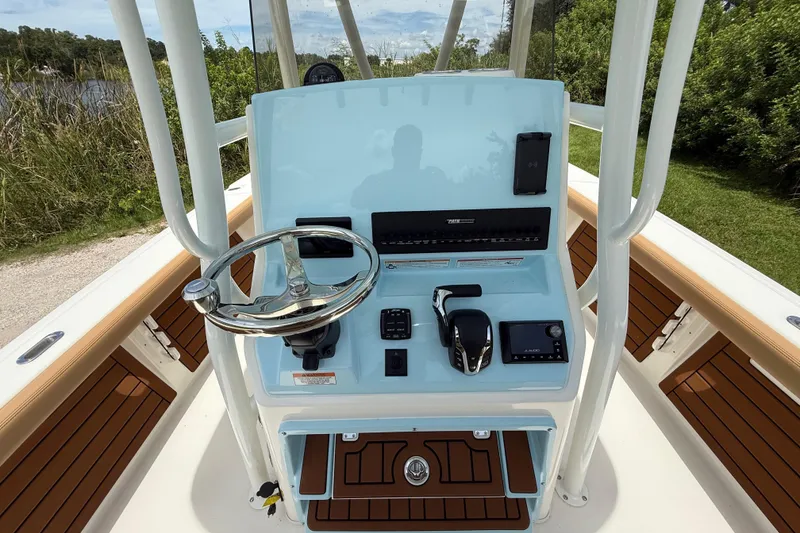 Slide: The Image of 2026 Pathfinder 2400 TRS boat console with steering wheel and controls, surrounded by lush greenery. - 15