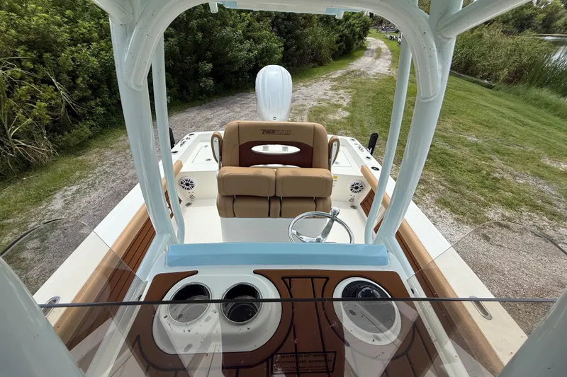 Slide: The Image of 2026 Pathfinder 2400 TRS boat interior with steering wheel and seating, surrounded by greenery. - 21