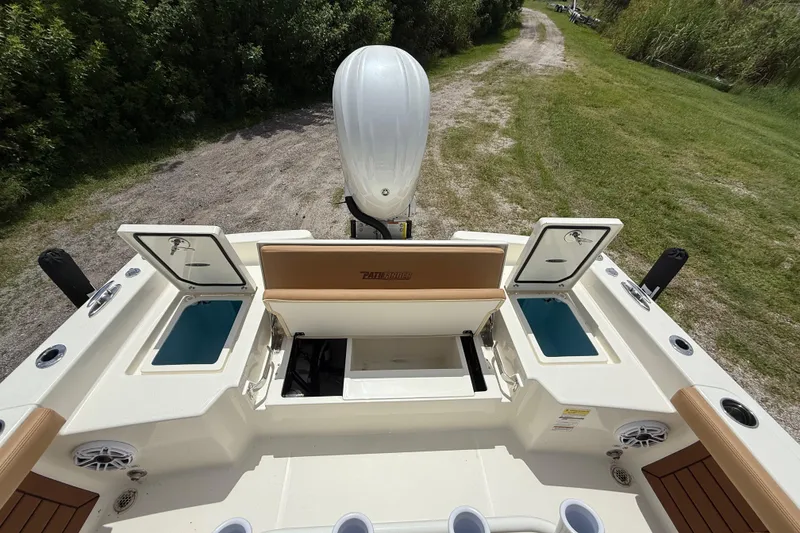 Slide: The Image of 2026 Pathfinder 2400 TRS boat with open storage compartments and outboard motor, on grassy path. - 25