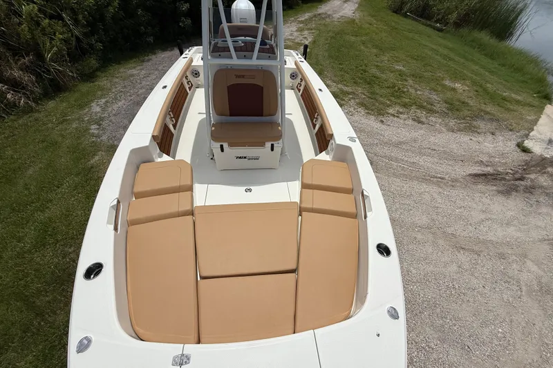 Slide: The Image of 2026 Pathfinder 2400 TRS boat with tan seating, docked on grassy shore. - 34