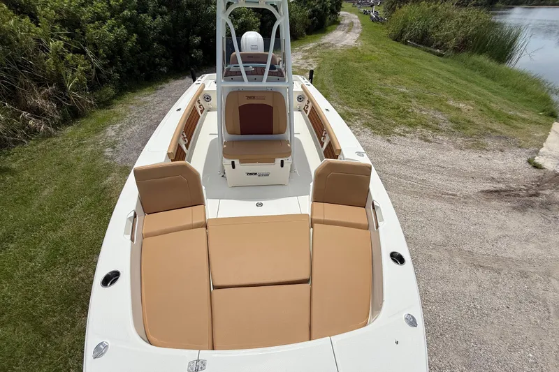 Slide: The Image of 2026 Pathfinder 2400 TRS boat with tan seating, parked on grassy path near water. - 35