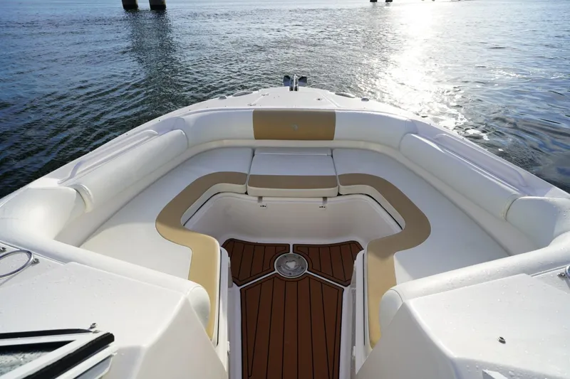 Slide: The Image of 2016 Edgewater 280 CX boat interior with cushioned seating and wooden deck, on calm water. - 10