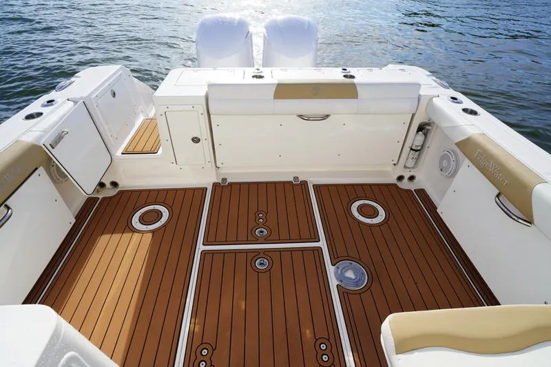 Slide: The Image of 2016 Edgewater 280 CX boat interior with teak flooring and white seating, on water. - 17