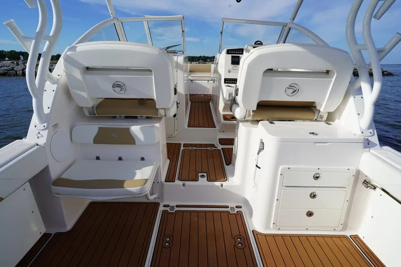 Slide: The Image of 2016 Edgewater 280 CX boat interior with seating and wooden flooring, docked by the water. - 19
