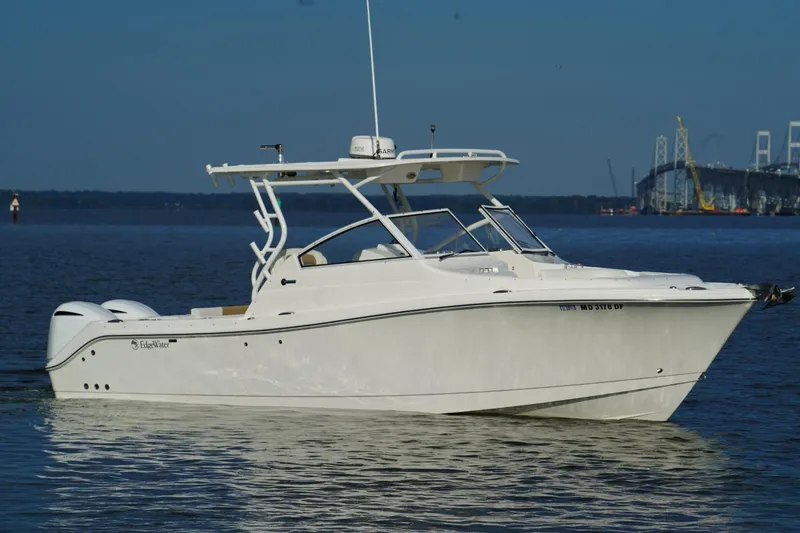 Slide: The Image of 2016 Edgewater 280 CX boat on calm water near a bridge. - 2