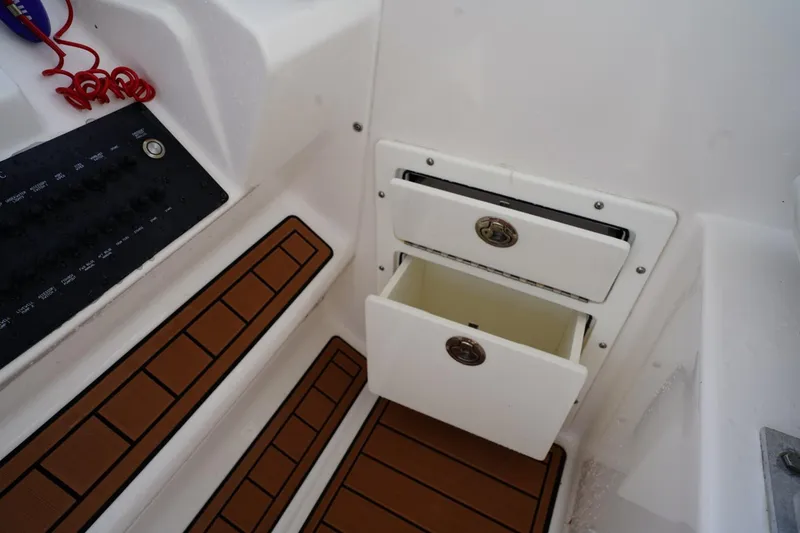 Slide: The Image of 2016 Edgewater 280 CX boat interior with open storage drawers and control panel. - 27