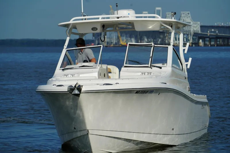 Slide: The Image of 2016 Edgewater 280 CX boat cruising on calm water near a bridge. - 5