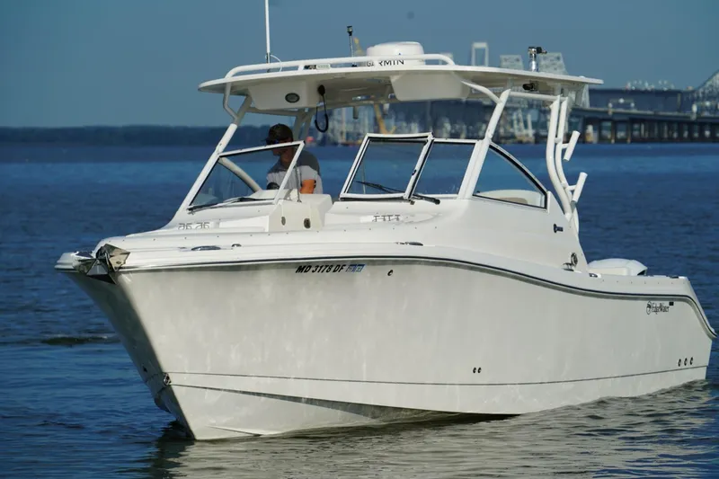 Slide: The Image of 2016 Edgewater 280 CX boat cruising on calm waters near a bridge. - 6