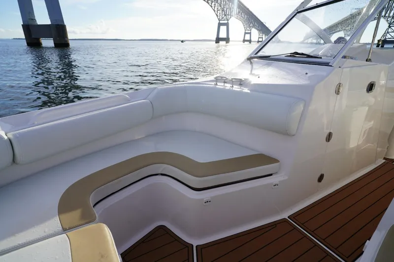 Slide: The Image of 2016 Edgewater 280 CX boat interior with cushioned seating, near a bridge on calm water. - 7
