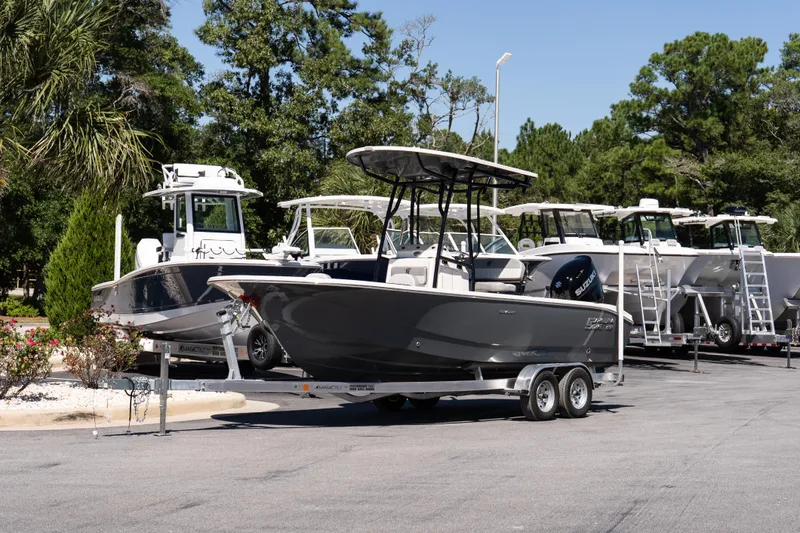 Slide: The Image of 2026 Carolina Skiff 22 Ultra Elite boat on trailer, surrounded by trees and other boats. - 2