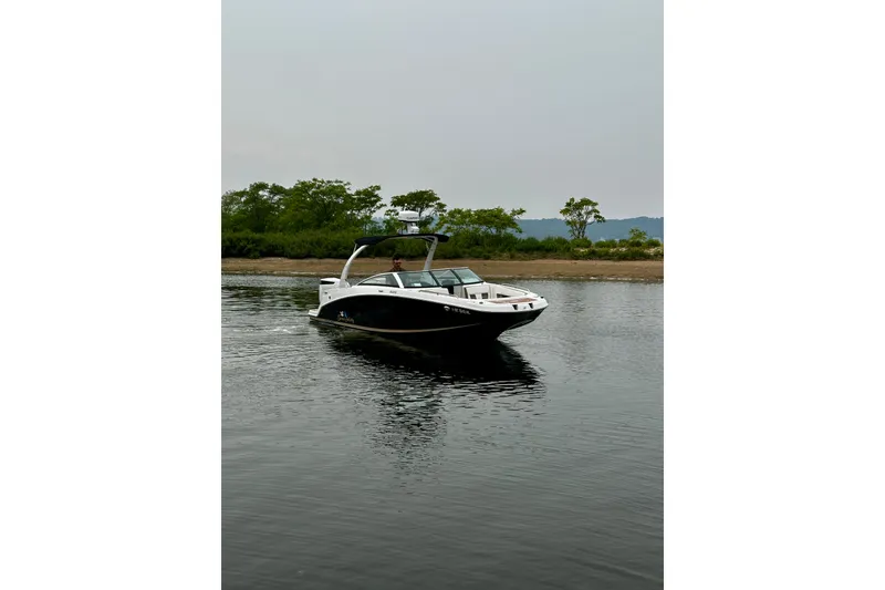 Slide: The Image of 2016 Four Winns Ho270 boat on calm water with lush green shoreline. - 16