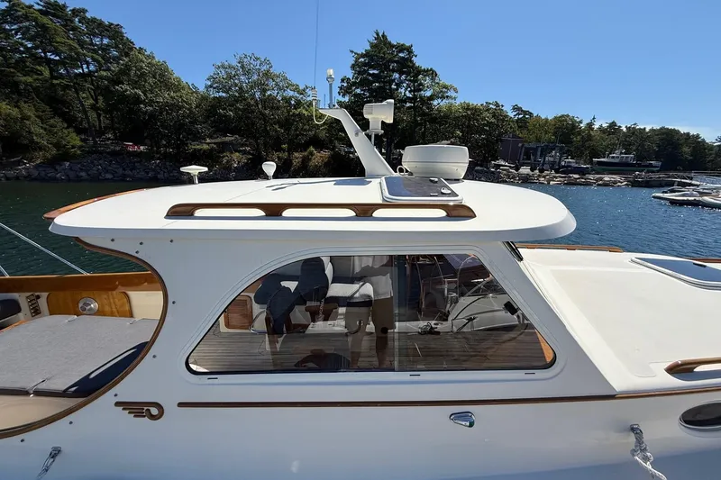 Slide: The Image of 2001 Hinckley Classic Picnic Boat on serene water with lush trees in the background. - 4