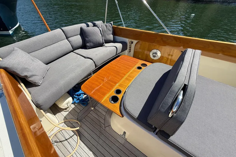 Slide: The Image of 2001 Hinckley Classic Picnic Boat interior with gray seating and wooden table on water. - 19