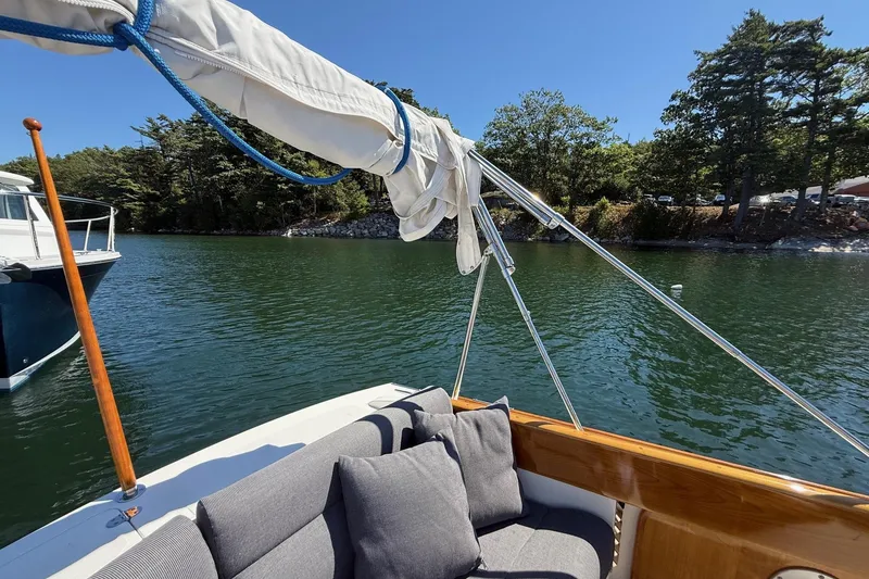 Slide: The Image of 2001 Hinckley Classic Picnic Boat on serene water, surrounded by lush trees. - 26