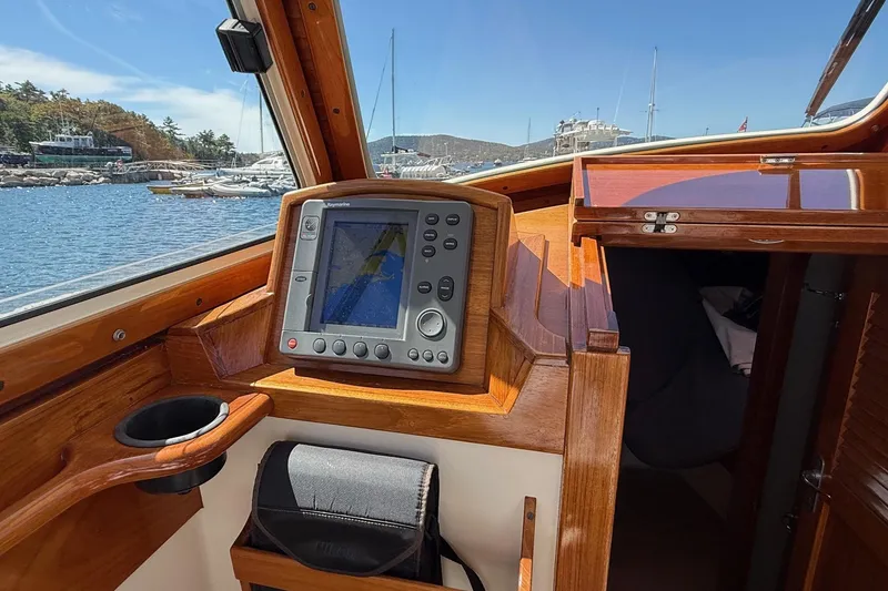 Slide: The Image of 2001 Hinckley Classic Picnic Boat interior with navigation system, wooden finish, and marina view. - 34