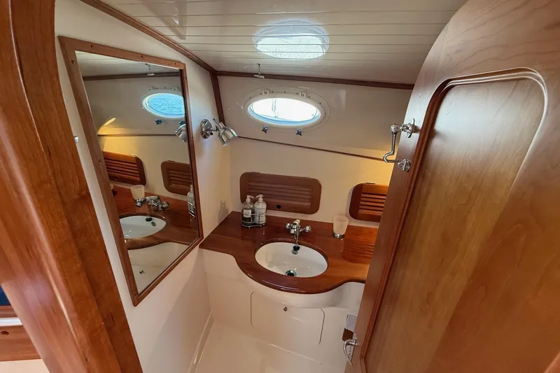 Slide: The Image of Elegant wooden interior of 2001 Hinckley Classic Picnic Boat bathroom with sink and mirror. - 58