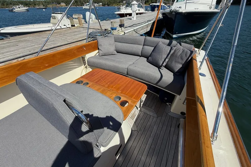 Slide: The Image of 2001 Hinckley Classic Picnic Boat with elegant seating and wooden table, docked by the water. - 20