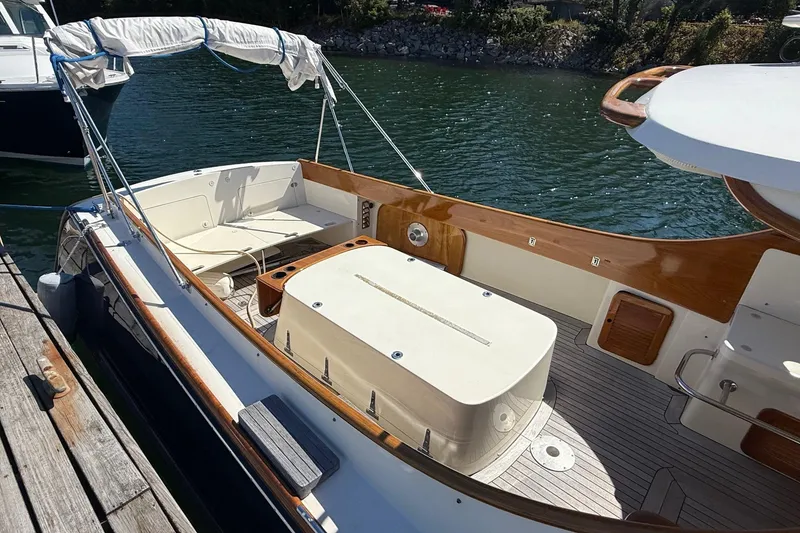 Slide: The Image of 2001 Hinckley Classic Picnic Boat docked, featuring elegant wood trim and spacious seating area. - 23