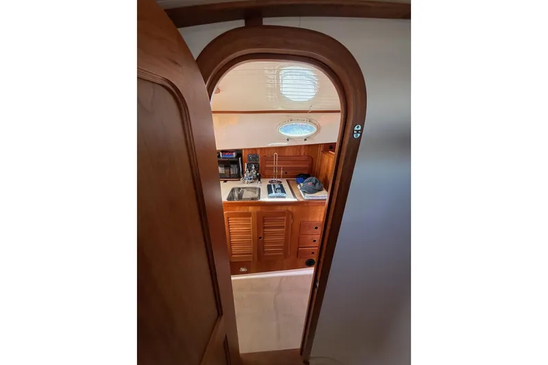 Slide: The Image of Interior view of 2001 Hinckley Classic Picnic Boat, featuring wooden cabinetry and compact kitchen area. - 60