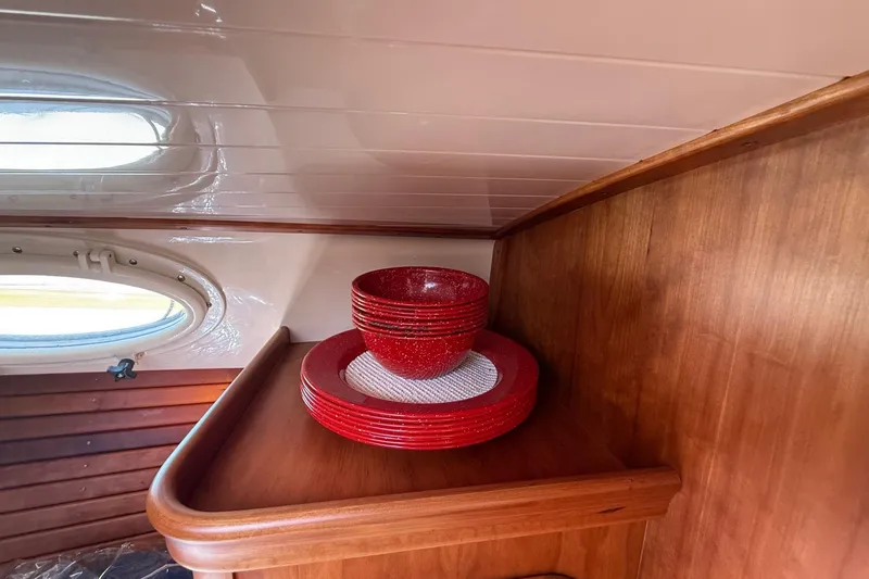 Slide: The Image of Red dishware set on wooden shelf inside 2001 Hinckley Classic Picnic Boat cabin. - 61