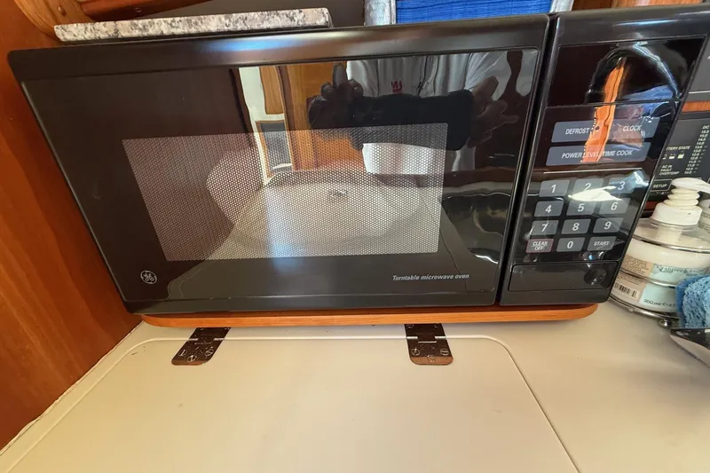 Slide: The Image of Microwave inside 2001 Hinckley Classic Picnic Boat galley, featuring control panel and wooden accents. - 65