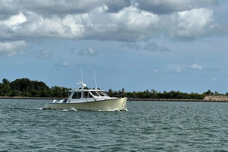Slide: The Image of 2002 True North 38 Heritage boat cruising on a calm lake under cloudy skies. - 2