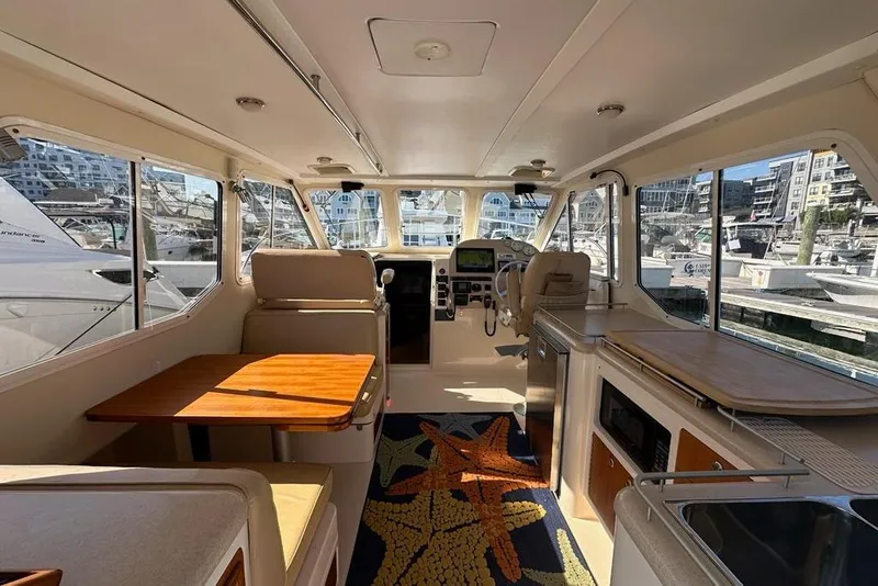 Slide: The Image of Interior of 2002 True North 38 Heritage yacht, featuring seating, table, and kitchen area. - 5