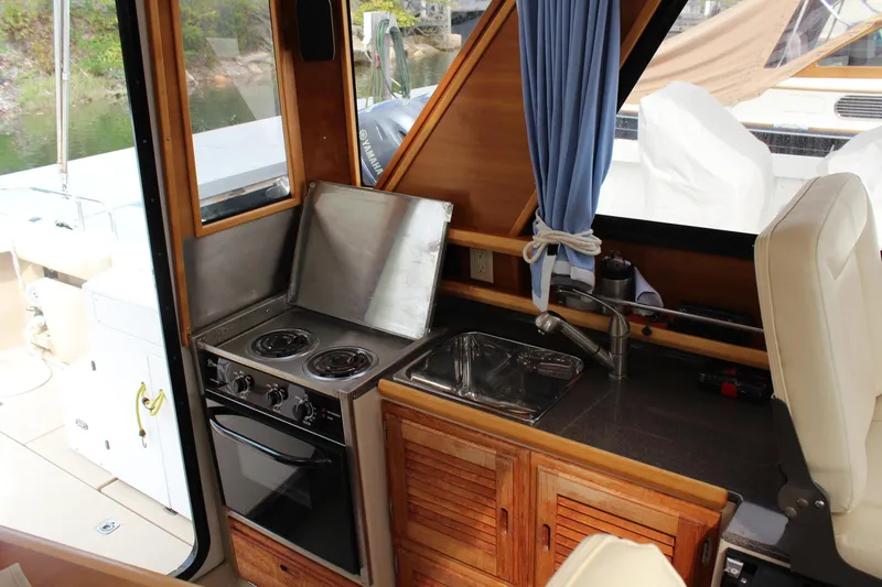 Slide: The Image of 2013 Cutwater 28 LE boat interior with stove, sink, and wooden cabinetry. - 23