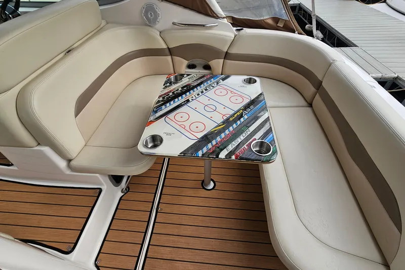 Slide: The Image of 2004 Chaparral Signature 310 boat interior with custom hockey-themed table and beige seating. - 10