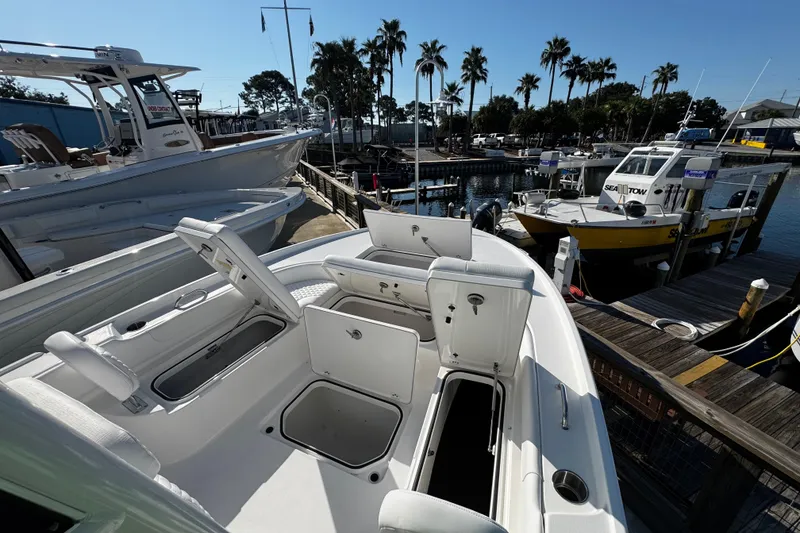 Slide: The Image of 2026 Caymas 24 HB boat with white seating, docked at a marina with palm trees. - 16