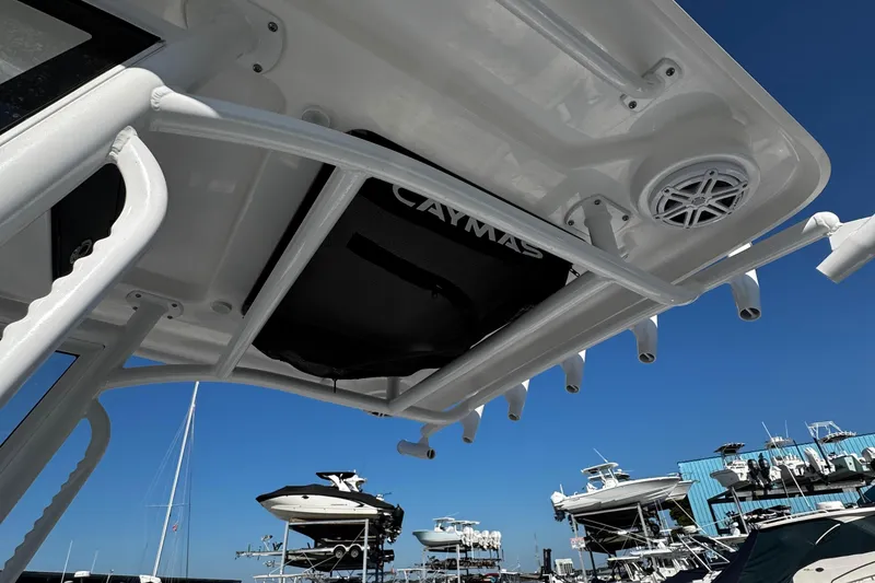 Slide: The Image of 2026 Caymas 24 HB boat interior with steering console and seating, under clear blue sky. - 22
