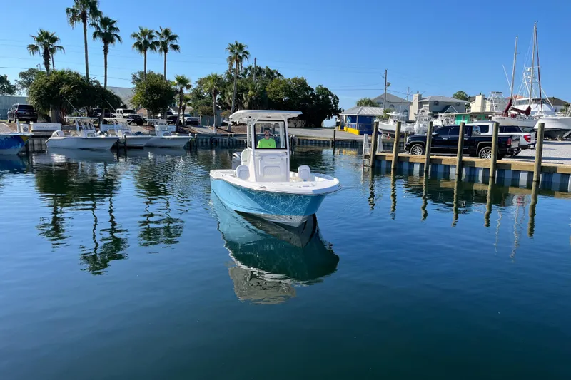Slide: The Image of 2026 Caymas 24 HB boat in marina, surrounded by palm trees and parked vehicles. - 5