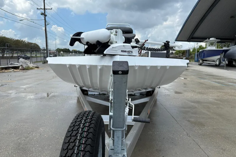 Slide: The Image of 2024 Alweld 2070cc boat on trailer with Minn Kota motor, parked outdoors. - 2