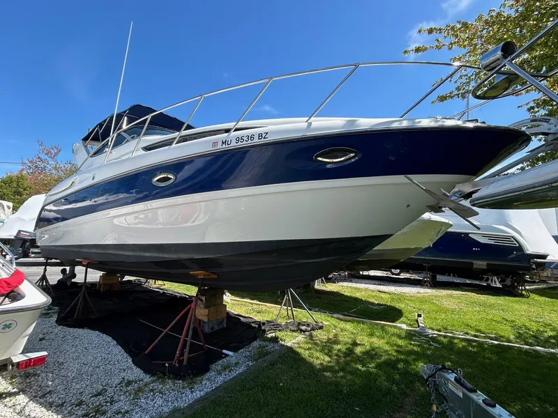 Slide: The Image of 2007 Bayliner 305 boat on stands, blue and white hull, sunny day. - 1