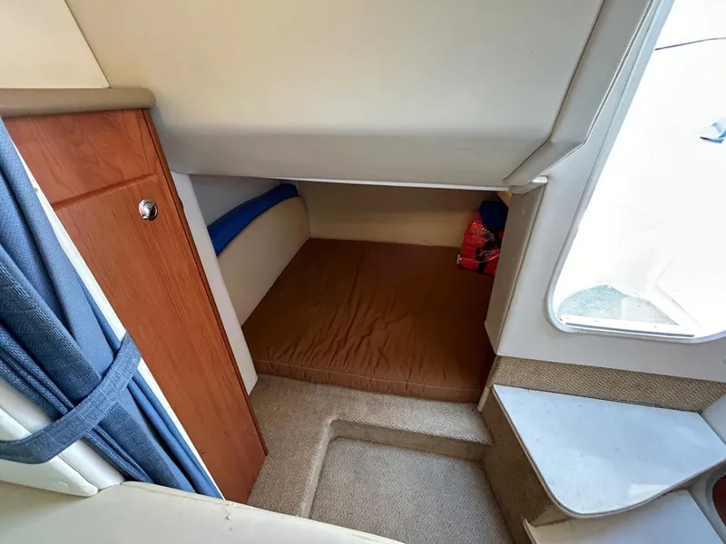 Slide: The Image of 2007 Bayliner 305 cabin interior with bed, wooden cabinet, and window view. - 19