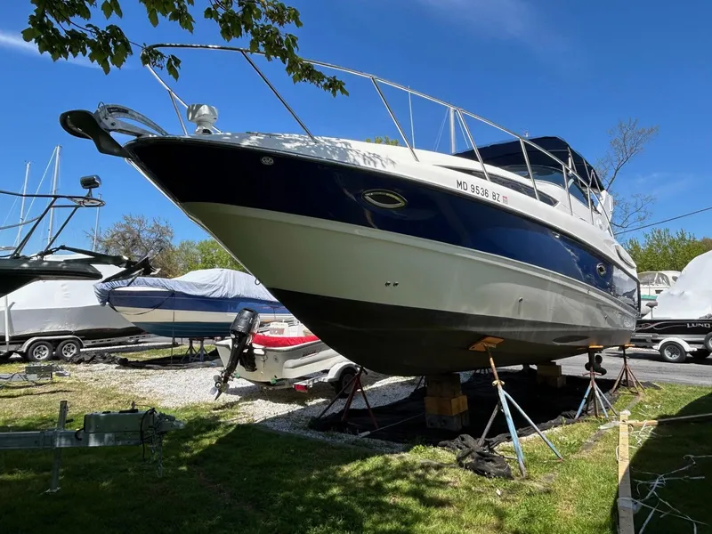 Slide: The Image of 2007 Bayliner 305 boat on stands, surrounded by other boats, under a clear blue sky. - 2