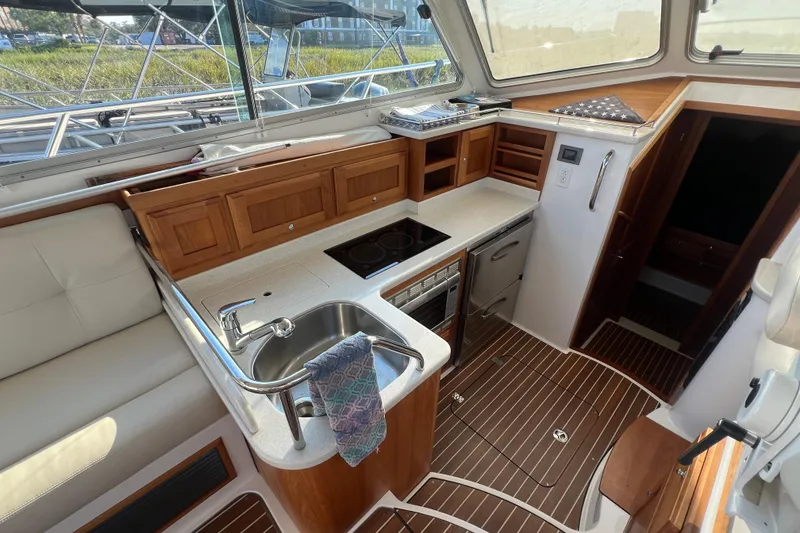 Slide: The Image of 2016 Back Cove 37 yacht interior with modern kitchen, featuring wood cabinetry and stainless steel sink. - 19