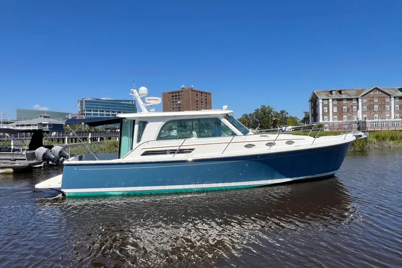 Slide: The Image of 2016 Back Cove 37 boat on water, blue hull, cityscape background. - 3