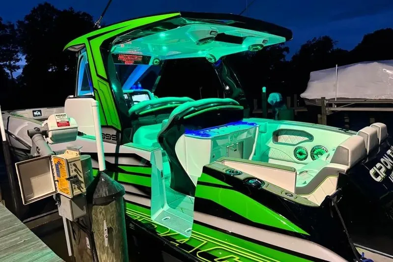 Slide: The Image of 2024 Deep Impact 399 Sport boat with vibrant green and blue LED lighting at night. - 10