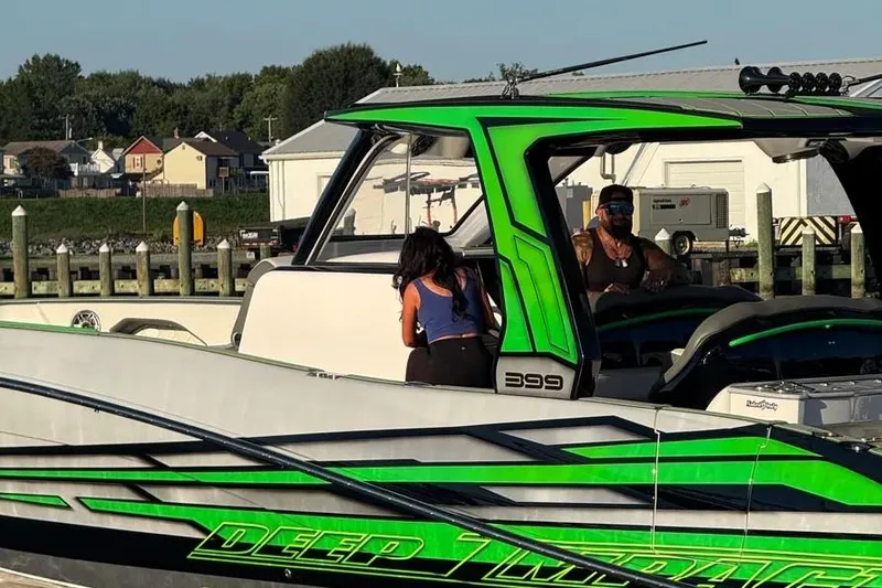 Slide: The Image of 2024 Deep Impact 399 Sport boat docked, featuring vibrant green accents and sleek design. - 11