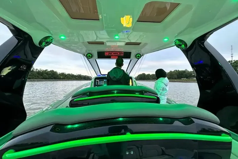 Slide: The Image of 2024 Deep Impact 399 Sport boat interior with green LED lighting on the water. - 12