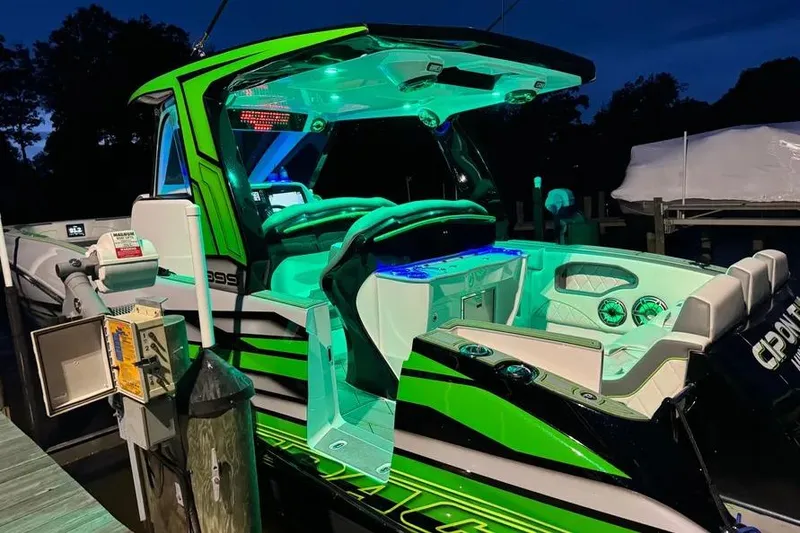 Slide: The Image of 2024 Deep Impact 399 Sport boat with vibrant green and blue LED lighting at night. - 13