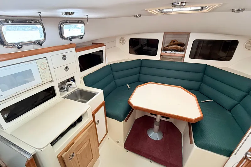Slide: The Image of Interior of 2001 Albin 28 Tournament Express with green seating and compact kitchen area. - 13