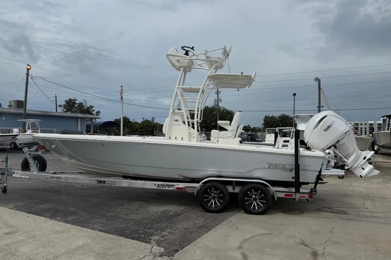 Slide: The Image of 2026 Pathfinder 2500 Hybrid boat on trailer, parked outdoors under cloudy sky. - 12