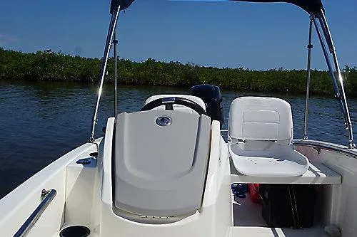 Slide: The Image of 2026 Boston Whaler 130 Super Sport boat interior with seating and console on calm water. - 7