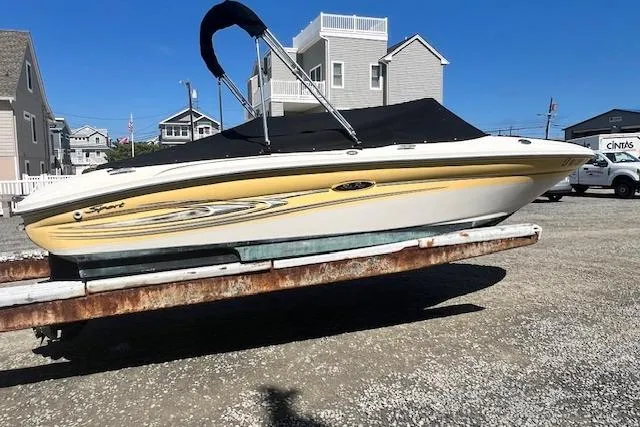Slide: The Image of 2005 Sea Ray 185 Sport boat on trailer, parked near coastal homes. - 2